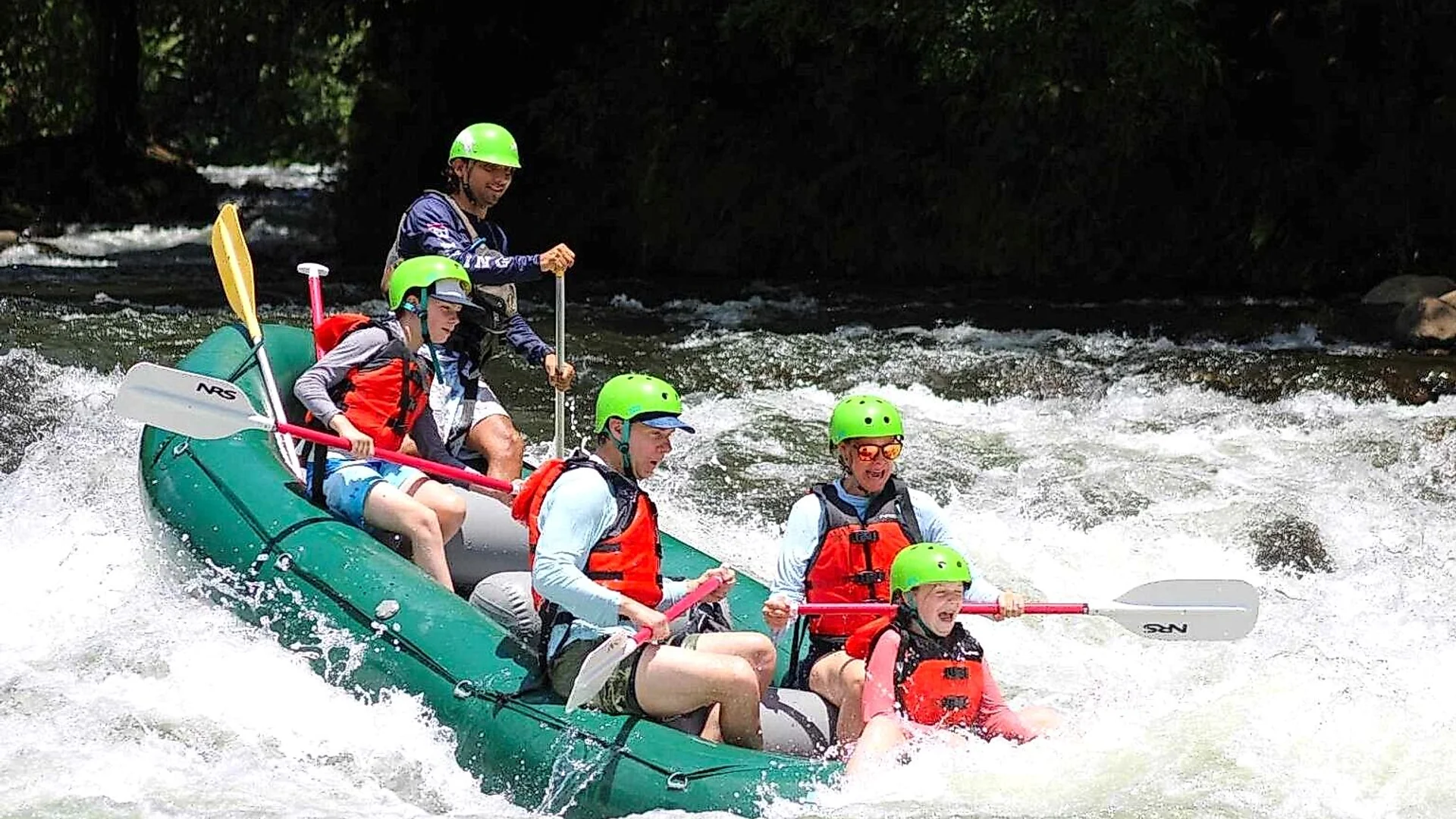 Group of adventurers navigating class III rapids on the Sarapiquí River, Costa Rica.