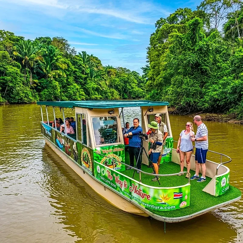 Touristes dans un bateau admirant la nature sous un ciel bleu dans la réserve faunique de Caño Negro.