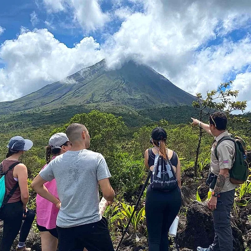 Randonnée guidée à travers les sentiers de lave volcanique avec le majestueux Arenal en arrière-plan.