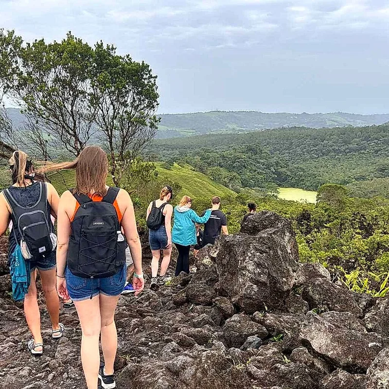 Group of hikers exploring rock formations from past eruptions.
